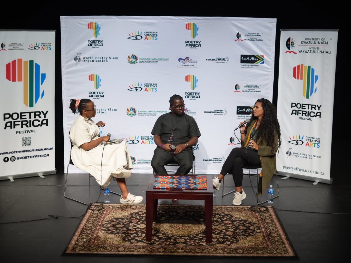 Qhakaza Mohare facilitating a panel conversation with Theophilus Atuahene Adu and Dayra Lee Montoyo Leandry at Poetry Africa 2026.